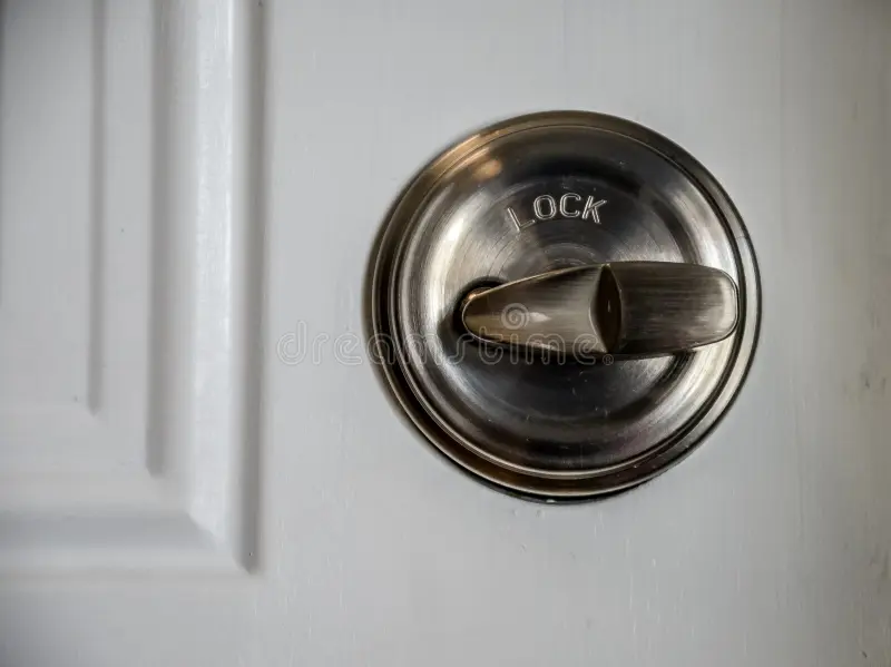 Close-up of a brass deadbolt on a brown wooden front door — the kind that swells and sticks in Florida humidity.