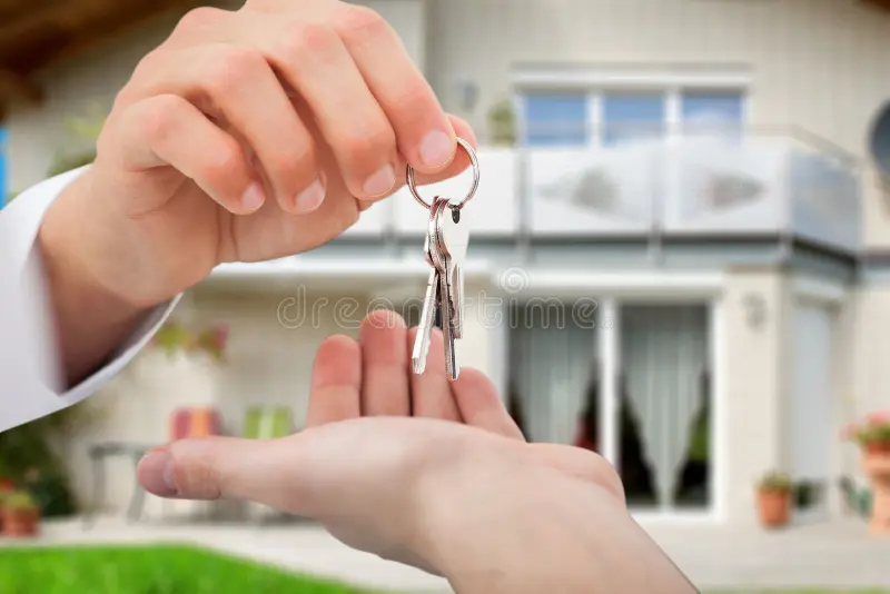Real estate agent handing house keys to a new homeowner in front of a Tampa Bay home.